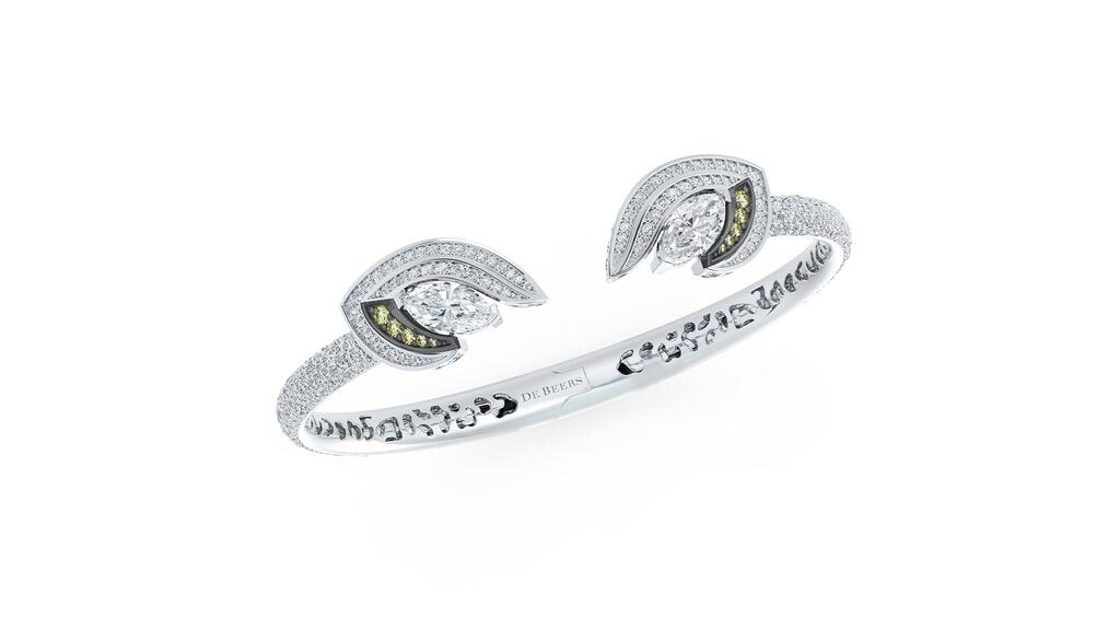 A white gold bangle with two marquise-shaped white diamonds accented by olive-green diamonds set in black rhodium-plated gold and a double halo of pavé-set diamonds creating an eye De Beers high jewelry Magnetism Bangle